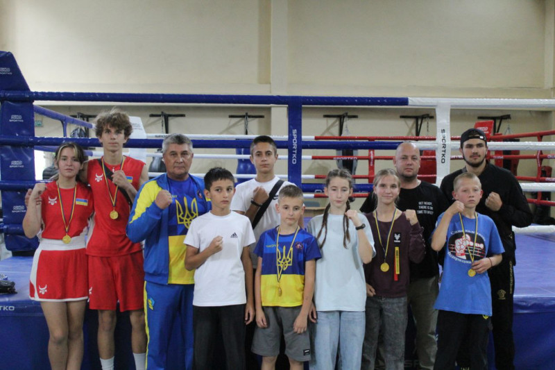 Спільне фото: юні спортсмени і спортсменки з медалями, чоловіки. Кожен тримає руку,  зціпивши кулак.