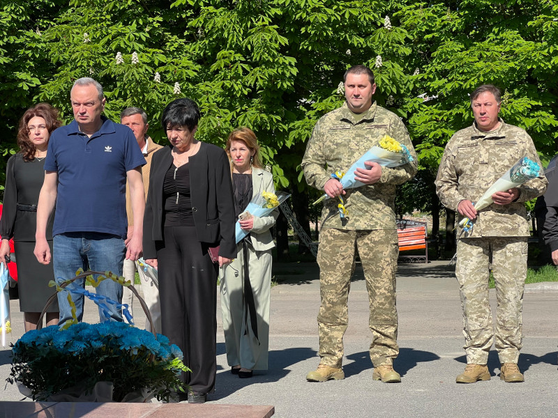 Спільне фото учасників заходу: керівництво міста та району, військові.  Схилили голови, тримають квіти. 