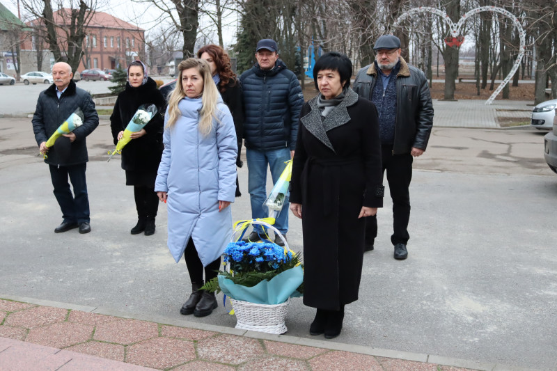 представники міської і районної влади стоять із квітами та кошиком із квітів 