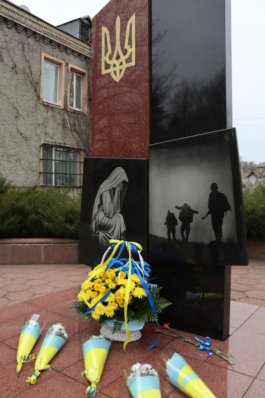 пам'ятний знак на честь загиблих Героїв, у підніжжя  - кошик із синьо-жовтими хризантемами та стрічками, поряд - поодинокі букети