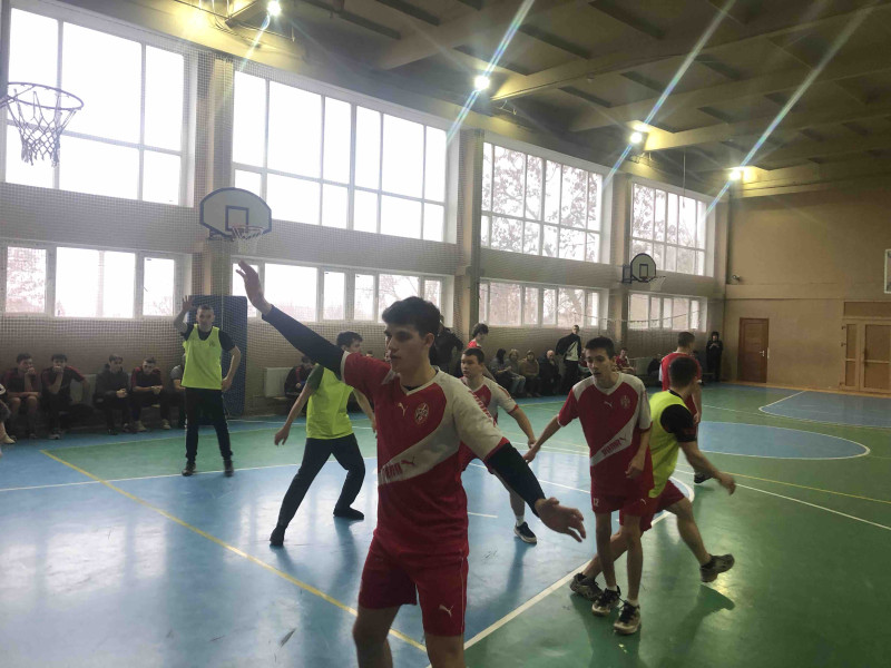 момент гри у спортивній залі: баскетболісти з однієї команди протидіють атакам із іншої