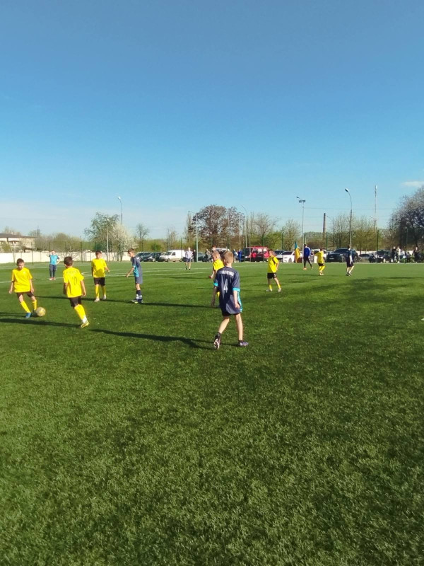 Момент гри на полі: футболісти у жовтих та синіх формах розігрують м'яч.