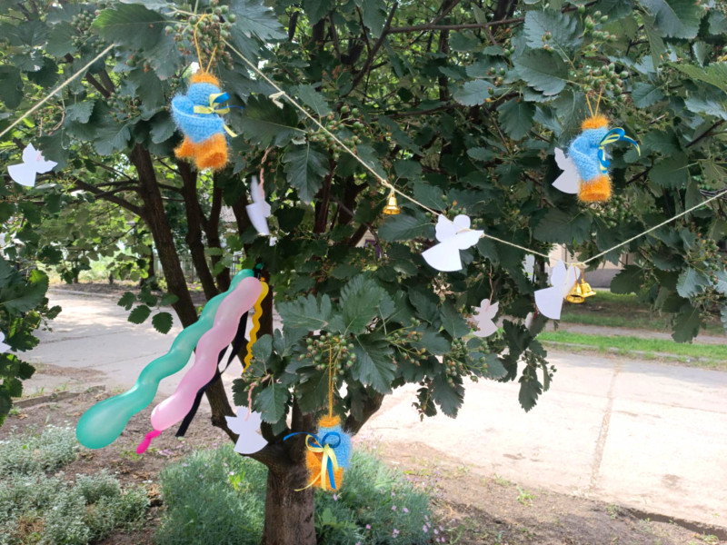 Дерево, на якому висять повітряні кульки, різні янголята.