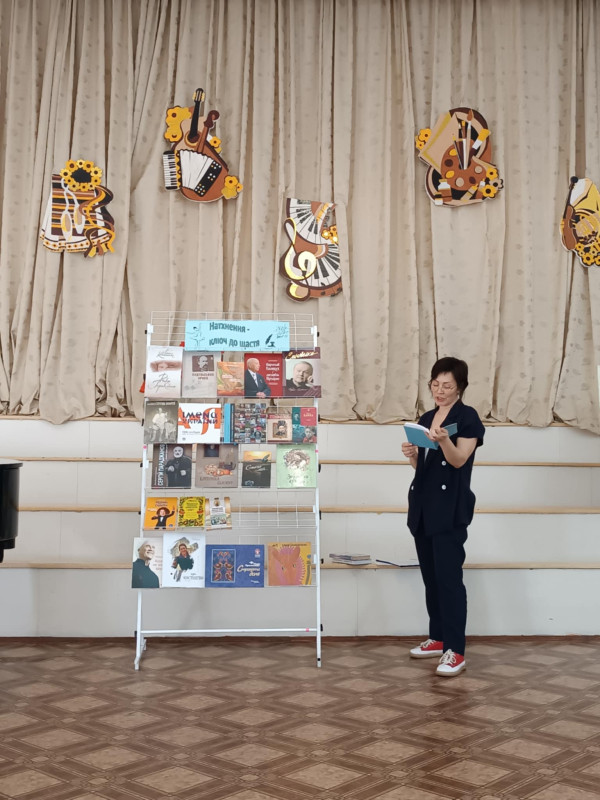 На сцені, біля книжкової виставки виступ бібліотекаря Руслани Шумовської