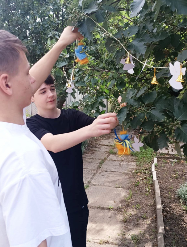 Два хлопці чіпляють на дерево янголят.