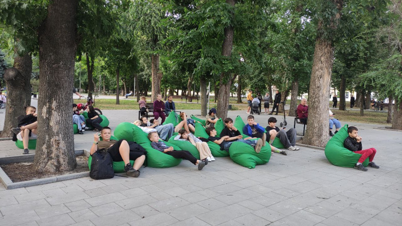 В парку на пуфах сидять діти та дивляться мультфільм