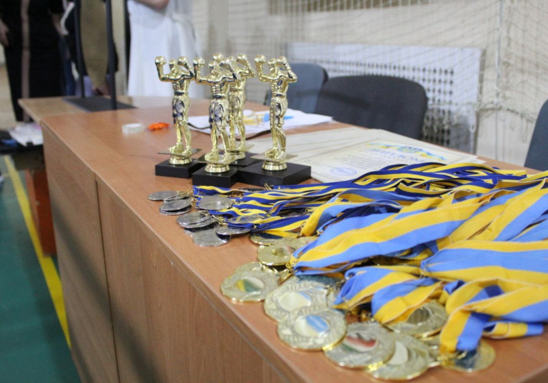 Золотисті статуетки боксерів, медалі, грамоти лежать на столі.