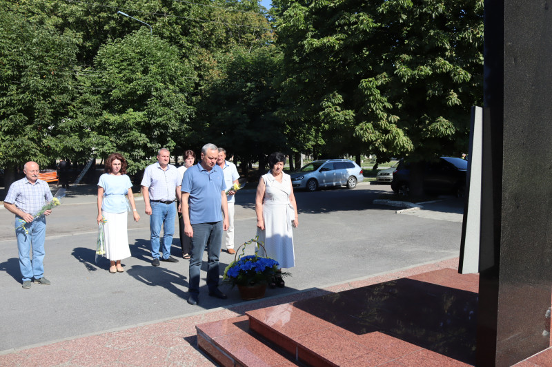 Міський голова Дмитро Зражевський та начальник Синельниківської районної військової адміністрації Світлана Назарчук, інші представники міської та районнної влади стоять у хвилині мовчання перед кошиком із квітами та пам'ятним знаком. 