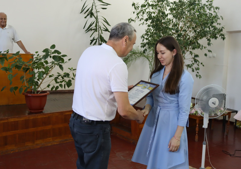 Міський голова Дмитро Зражевський вручає відзнаку  молодій дівчині, тисне руку.
