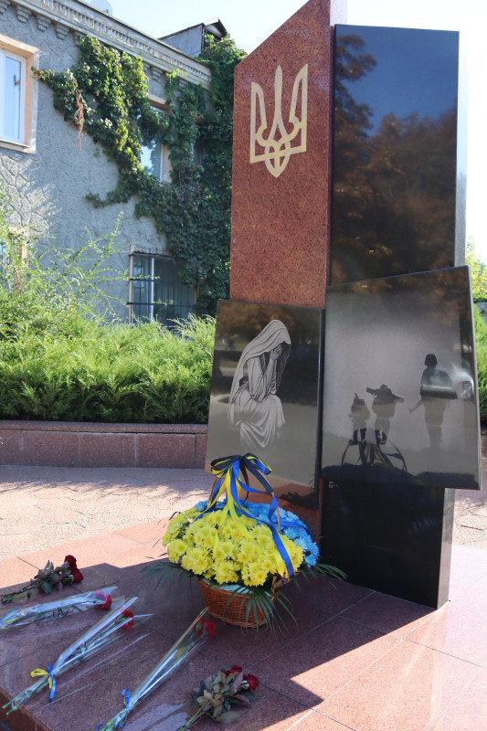 Пам'ятний знак загиблим захисникам і захисницям. У підніжжя - кошик із квітами, окремі букети.