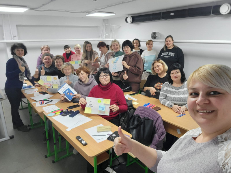 Спільне фото учасниць тренінгу: жінки сидять/стоять за партами, усміхнені, в руках тримають навчальні матеріали.
