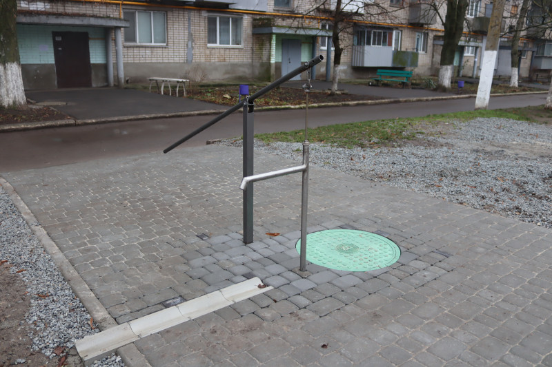 Нова криниця біля багатоповерхівки. Територія навколо викладена тротуарною плиткою.