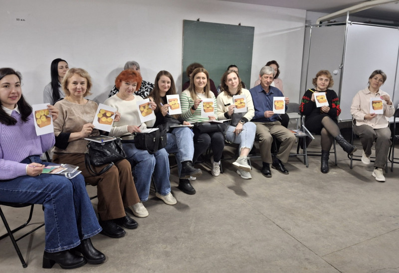 Спільне фото учасників заходу, які сидять півколом, тримають у руках картинки.